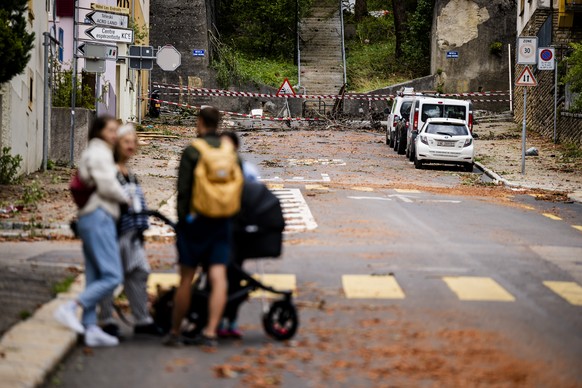 Des personnes regardent les debris dans une rue, un jour apres passage de la forte tempete le mardi 25 juillet 2023 a La Chaux-de-Fonds. Le deblaiement des materiaux et la reparation des infrastructur ...
