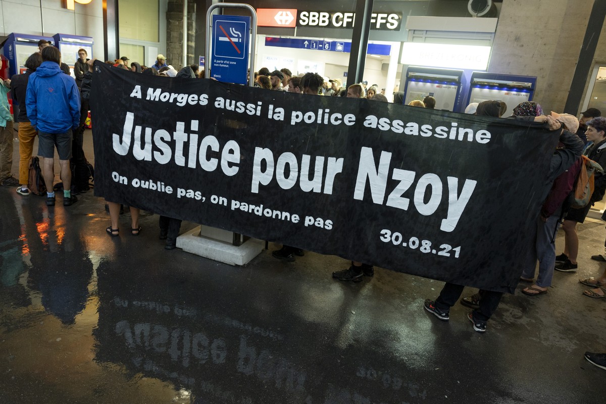 Des personnes tiennent une banderoles " a Morges aussi la police assassine Justice pour Nzoy - on ne pardonne pas, on oublie pas" lors d'un rassemblement devant l'entree de la gare ...