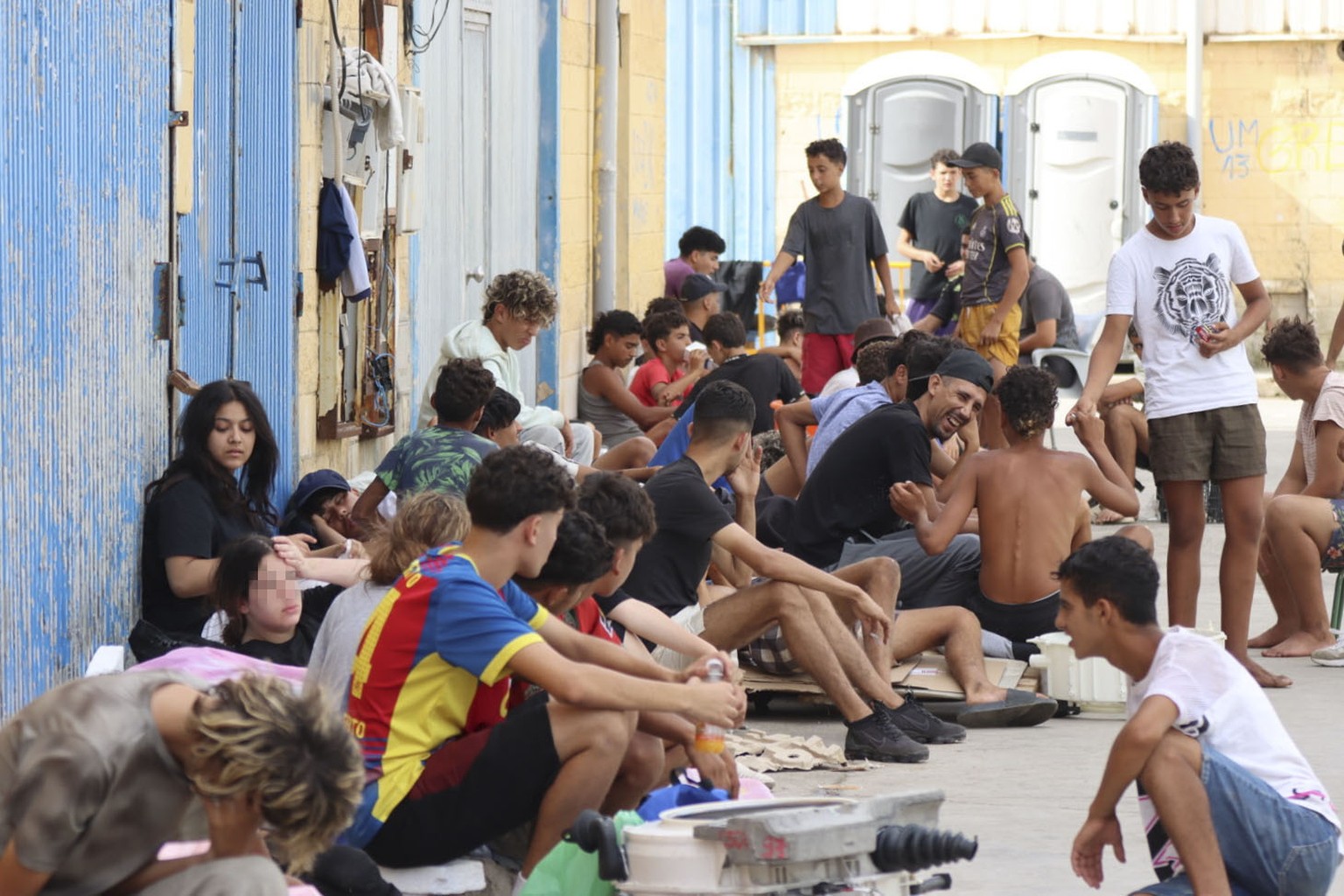 epa13148246 Migrants who entered Ceuta by swimming or on foot from Morocco sit on a street in Ceuta, Spain, 03 August 2026. Surveillance along the Tarajal border, both at sea and on land, as well as n ...