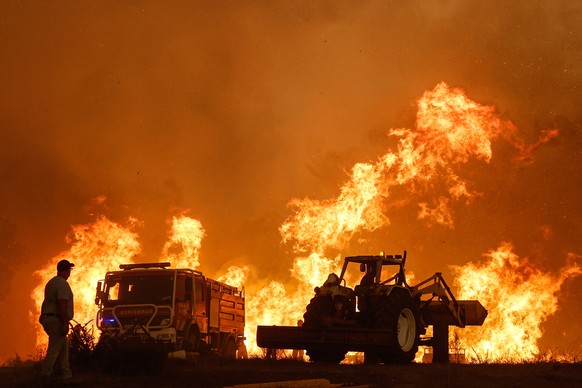 epa10789282 A man watches the fire in the municipality of Odemira, 07 August 2023. The fire, which broke out in the Baiona area, in the parish of S?