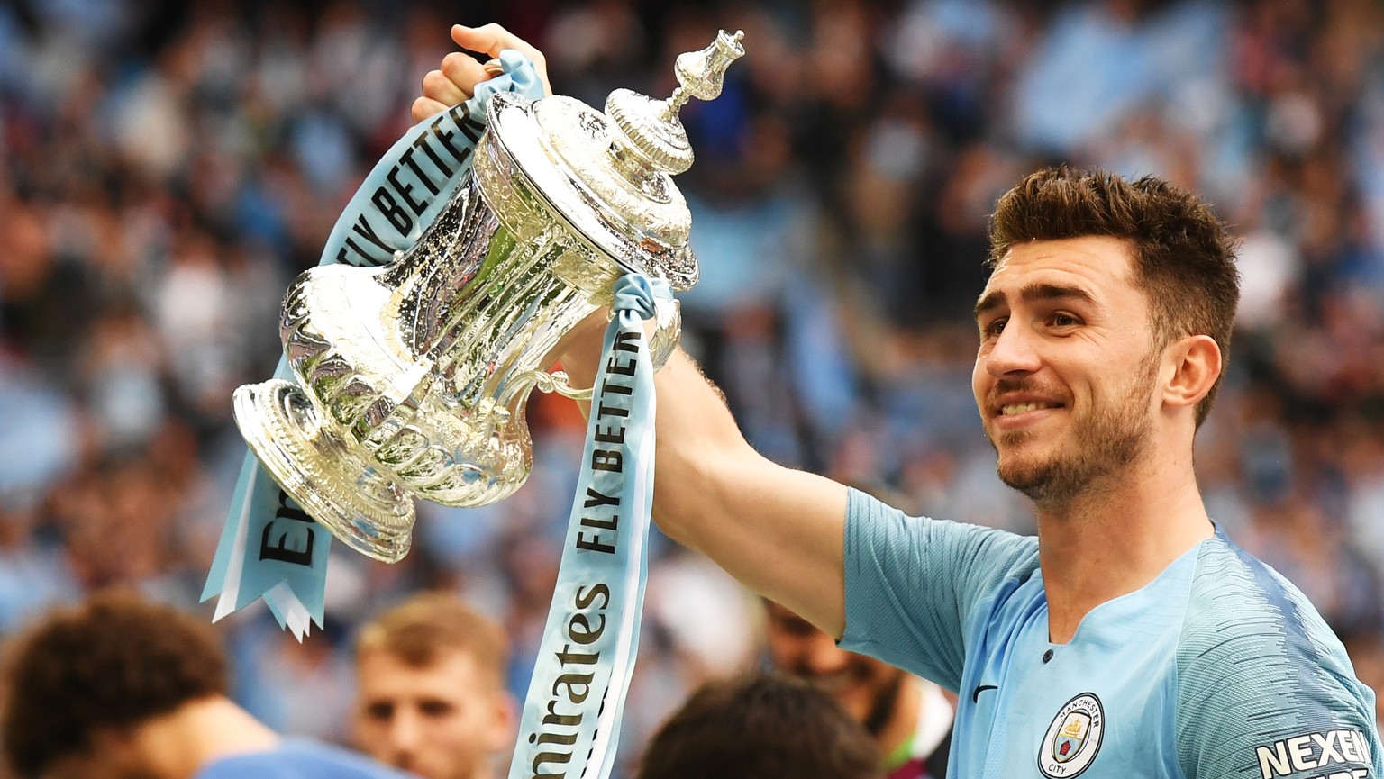 epa07582420 Aymeric Laporte of Manchester City lifts the trophy after the English FA Cup final between Manchester City and Watford at Wembley Stadium in London, Britain, 18 May 2019. Manchester City w ...