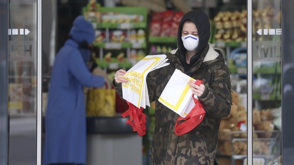 A person wearing a protective mask leaves a supermarket in Vienna, Austria, Monday, March 30, 2020. In Austria it will be mandatory to wear protective masks in supermarkets. The Austrian government ha ...