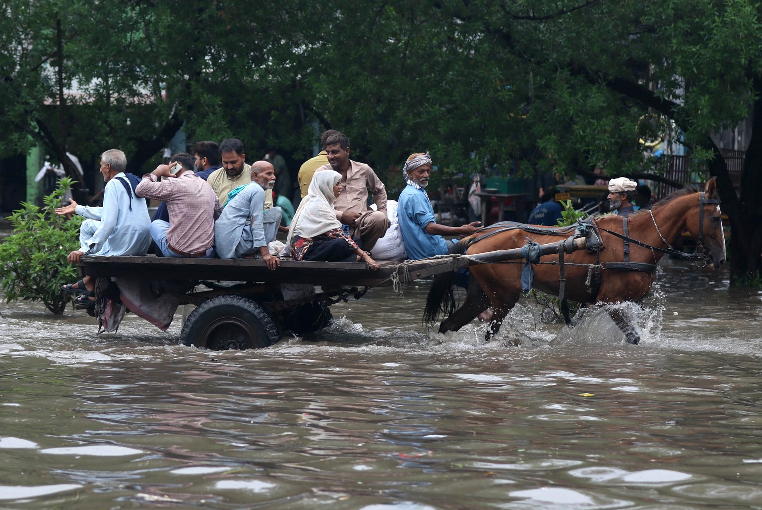epa11515512 People and vehicles make their way through a water-logged street after heavy rainfall in Lahore, Pakistan, 01 August 2024. Lahore experienced heavy monsoon rains on Thursday, with 350 mill ...