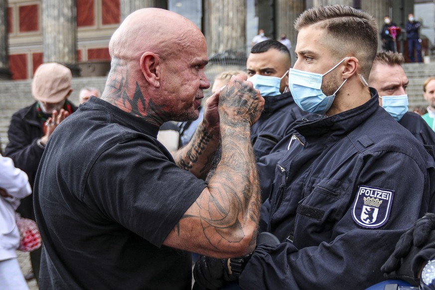 epa08540604 A protester talks to German police officers during an anti-restrictions protest lead by German vegan chef Attila Hildmann, at the Lustgarten park in Berlin, Germany, 11 July 2020. Hildmann ...