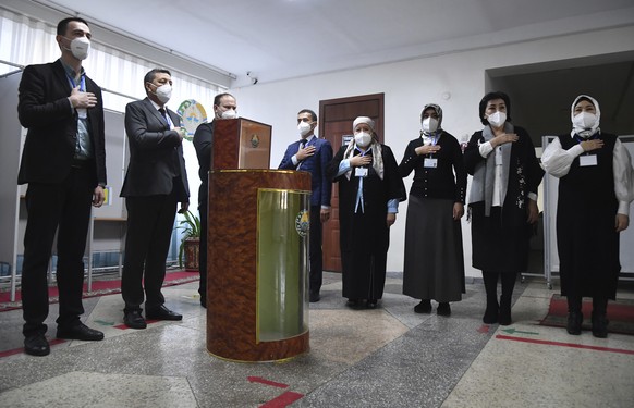 Members of an election commission listen to the national anthem at a polling station during the presidential election in Tashkent, Uzbekistan, Sunday, Oct. 24, 2021. Uzbekistan&#039;s President, Shavk ...