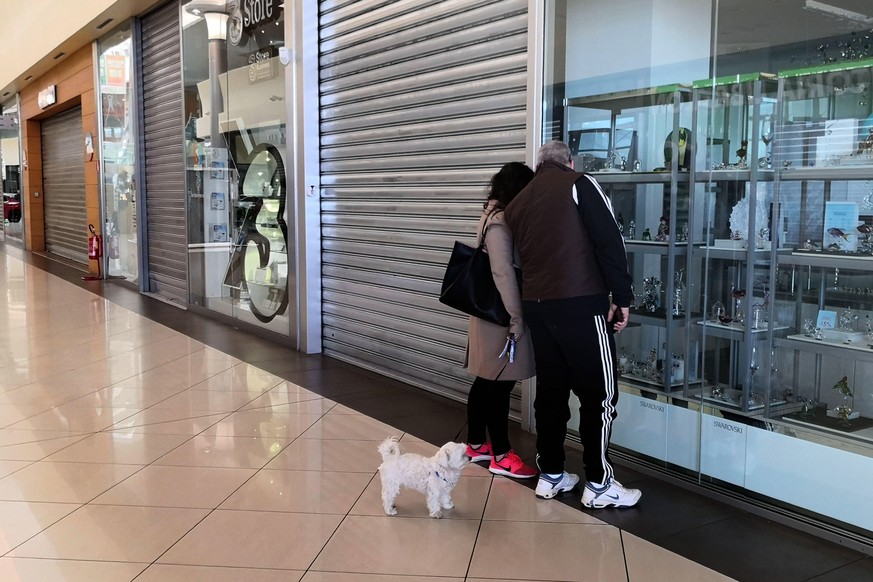 epa08278645 People peer into closed shops inside a mall in Padua, northern Italy, 08 March 2020. The Italian authorities have taken the drastic measure of shutting off the entire northern Italian regi ...