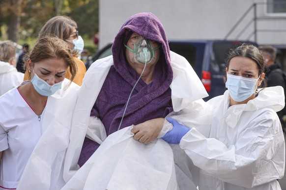 Medical staff support a patient breathing through an oxygen mask after a fire in the COVID-19 ICU section of the Hospital for Infectious Diseases in the Black Sea port of Constanta, Romania, Friday, O ...