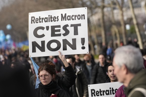 Protesters hold a poster lecture "Macron's retirement plan, it's no!" march during a demonstration against a reform aimed at raising the minimum retirement age from 62 to 64, Thursday, February 16 ...