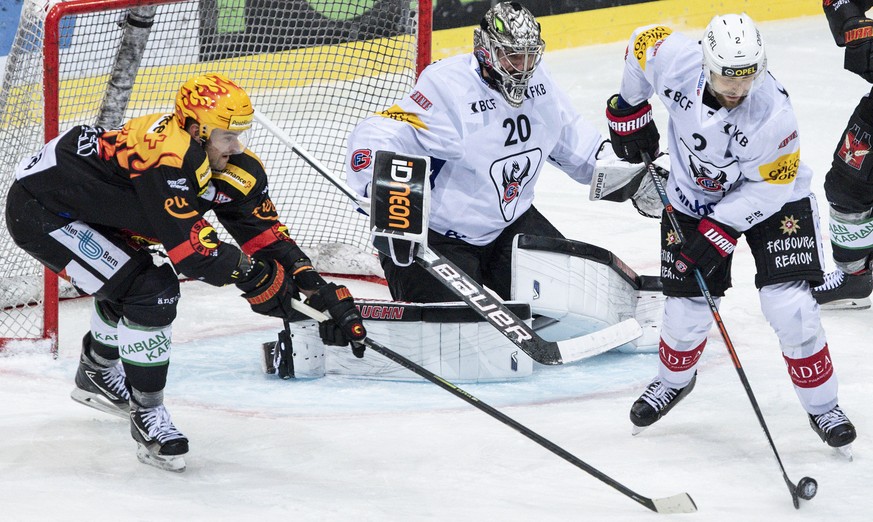 Berns PostFinance Topscorer Dustin Jeffrey, links, im Duell mit Gotterons Torhueter Reto Berra, Mitte, und Marc Abplanalp im Eishockey Meisterschaftsspiel der National League zwischen dem SC Bern und  ...