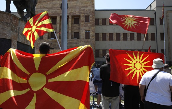 People wave the old and the current national flags and chant slogans during a protest in front of the parliament building in Skopje, North Macedonia, on Saturday, July 16, 2022. North Macedonia parlia ...