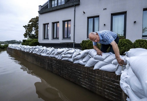 epa09349770 A resident of the evacuated Arcen looks at the rising water of the river Maas, in Arcen, North Limburg, The Netherlands, 17 July 2021. Heavy rainfall has led to floods and damages in vario ...