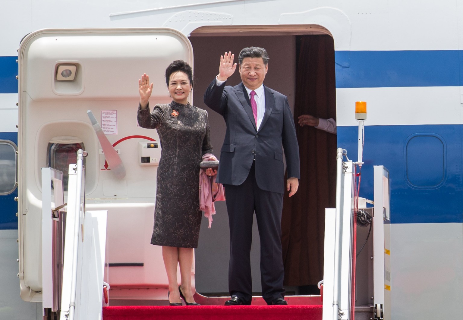 epa06059051 Chinese President Xi Jinping (R) and First Lady Peng Liyuan (L) wave as they depart to Beijing, at Hong Kong International Airport in Hong Kong, China, 01 July 2017. Chinese President Xi J ...