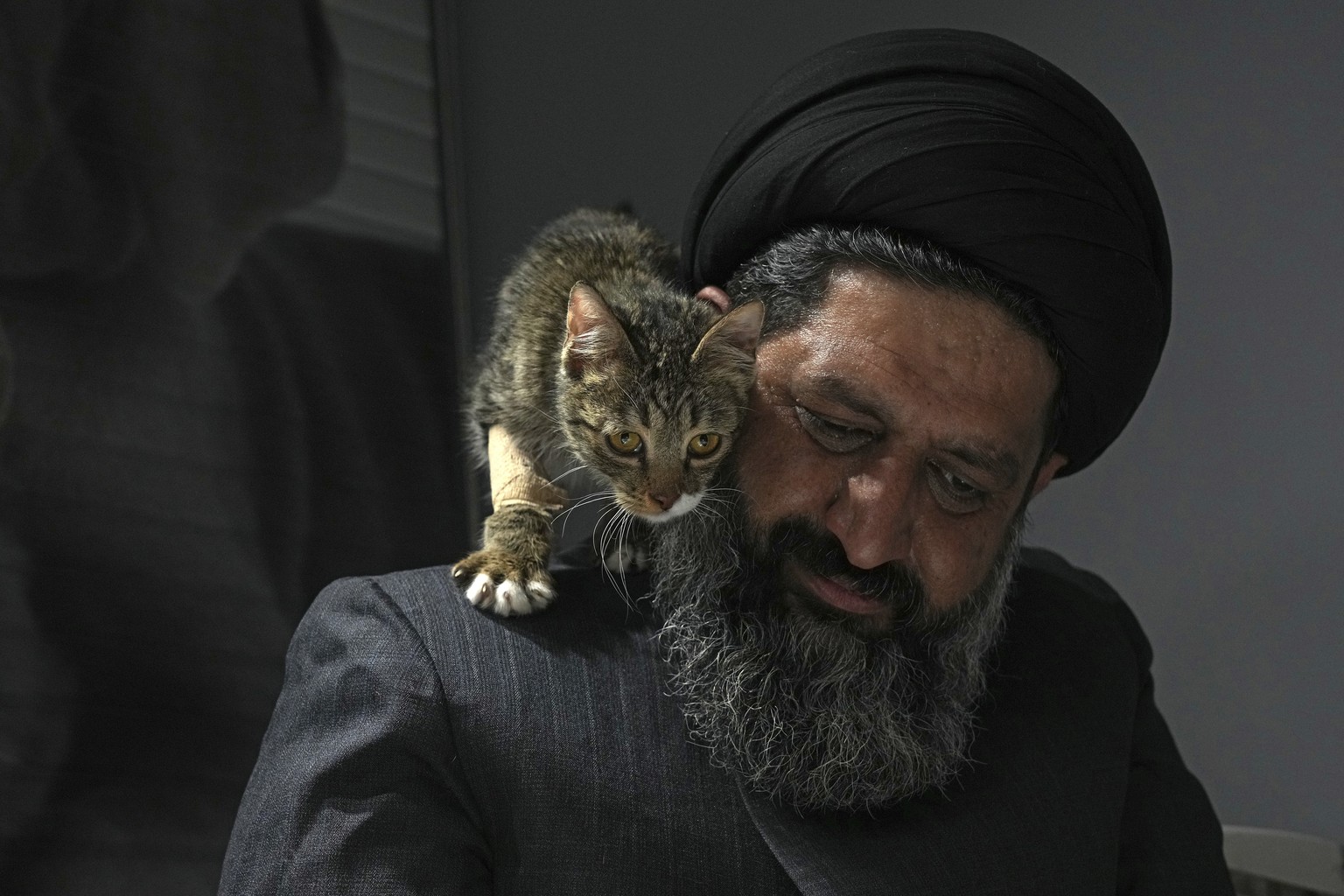 An injured stray cat walks on the shoulder of Iranian cleric Sayed Mahdi Tabatabaei after treatment at a veterinary clinic in Tehran, Iran, Friday, May 19, 2023. It&#039;s rare these days for a turban ...