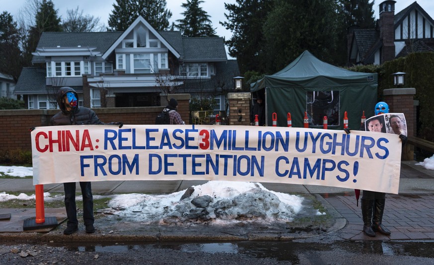 epa08145323 A couple of protesters stand outside the home of Meng Wanzhou, Chief Financial Officer of Huawei, before her departure to the BC Supreme Court in Vancouver, British Columbia, Canada, 20 Ja ...