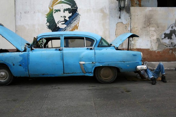 Abel Gomez Goitia, 50, repairs his car next to an image of Cuban revolutionary leader Ernesto "Che" Guevara in Old Havana, Saturday, July 28, 2007. (AP Photo/Rodrigo Abd)