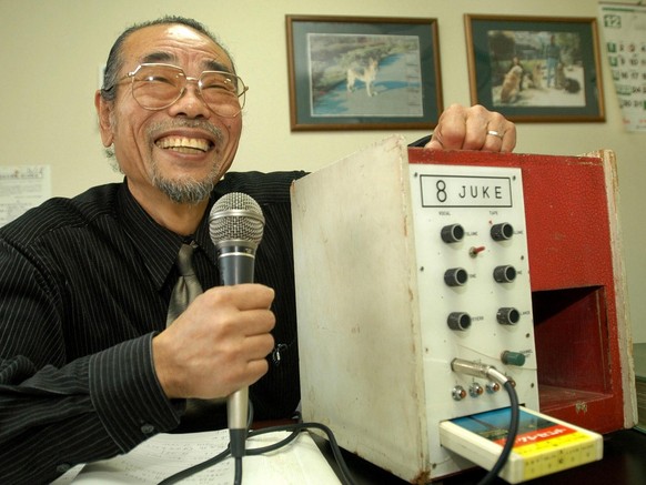 Holding a microphone, Daisuke Inoue grins as he shows his 1971 invention the &quot;8-Juke,&quot; a red and white wooden box that combined microphone, amplifier and an eight-track tape player, at his o ...