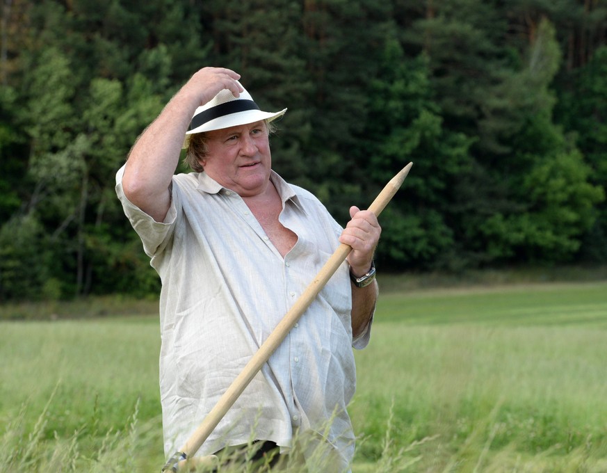 In this photo taken Wednesday, July 22, 2015, French actor Gerard Depardieu holds a hand scythe in the presidential residence of Ozerny, outside Minsk, Belarus. Depardieu has frequented the former Sov ...