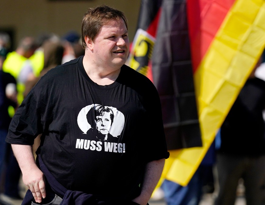 epa06766304 A man wear a shirt reading &#039;Merkel must go&#039; during a gathering of the &#039;Alternative for Germany&#039; (AfD) party hold flags in Berlin, Germany, 27 May 2018. The AfD has call ...