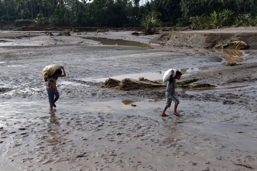 epa06403708 Filipino villagers carry belongings in flood hit town of Salvador, Lanao del Norte province, Philippines, 23 December 2017. According to news reports, Tropical storm Tembin brought mudslid ...