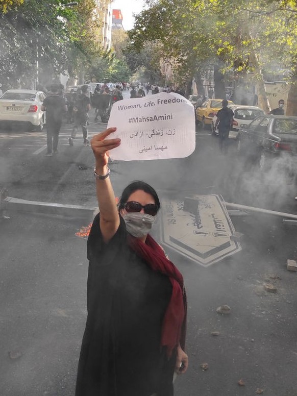 TEHRAN, IRAN - OCTOBER 01: (EDITORS NOTE: Image taken with mobile phone camera.) A protester holds up a note reading &quot;Woman, Life, Freedom, #MahsaAmini&quot; while marching down a street on Octob ...