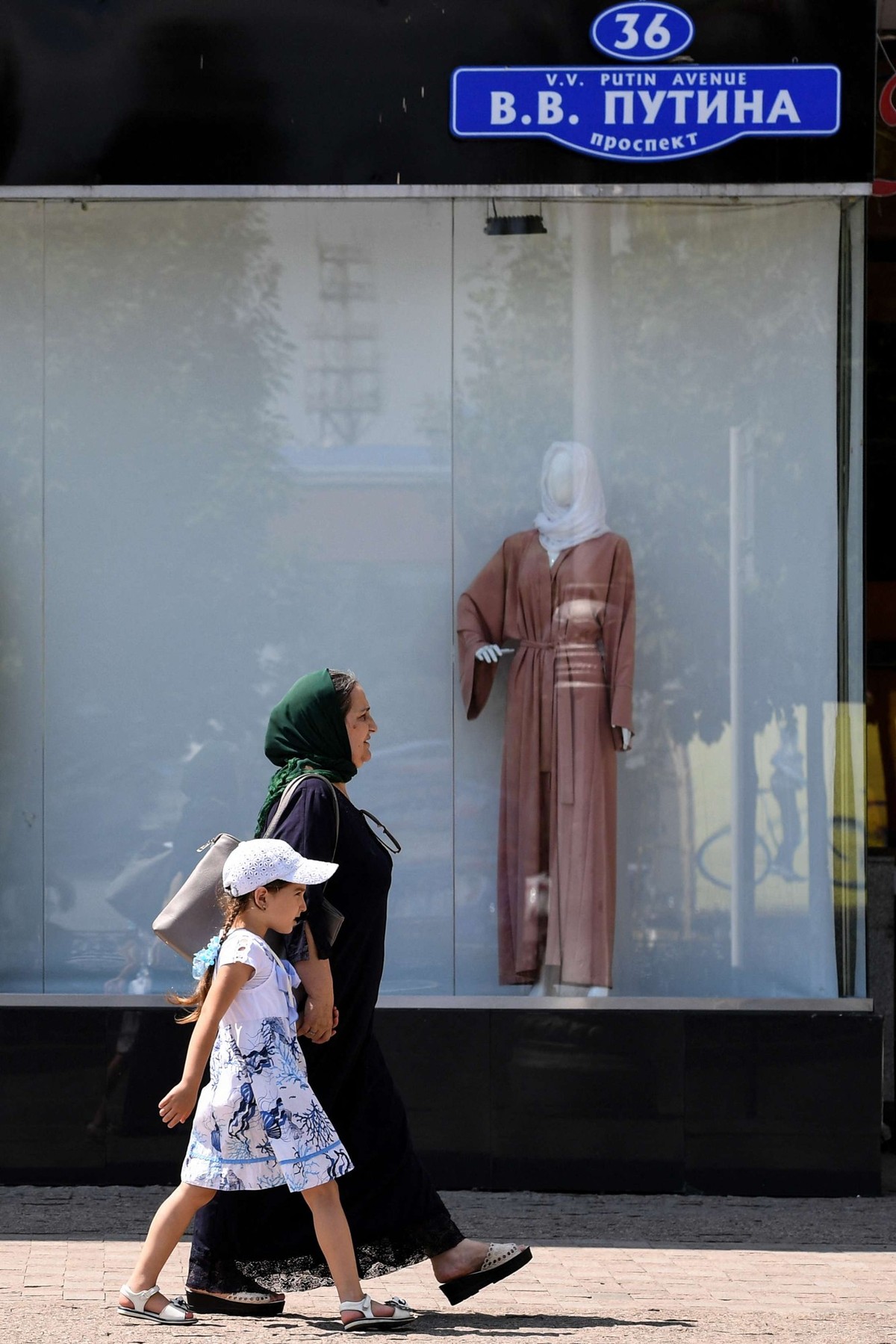 Une femme et un enfant passent devant une boutique vendant des vêtements islamiques pour femmes, dans le centre de Grozny, le 26 juillet 2017.