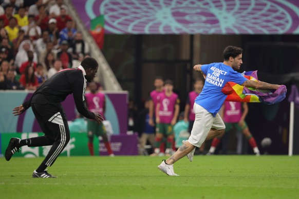 epa10335301 A steward (L) chases a pitch intruder during the FIFA World Cup 2022 Group H football match between Portugal and Uruguay at Lusail Stadium in Lusail, Qatar, November 28, 2022. EPA/Abir Sultan