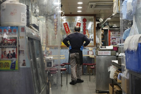 A waiter waits for customers at an empty restaurant in Hong Kong, Monday, Feb. 21, 2022. (AP Photo/Vincent Yu)