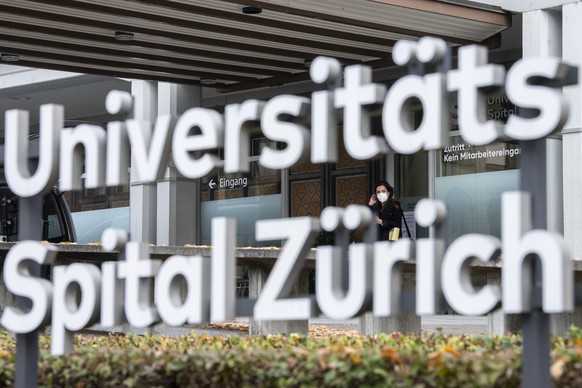 Menschen mit Atemschutzmasken bewegen sich vor dem Haupteingang vom Universitaets Spital Zuerich, aufgenommen am Dienstag, 10. November 2020 in Zuerich. (KEYSTONE/Ennio Leanza).