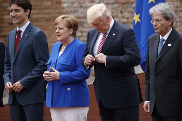 President Donald Trump adjusts his jacket during a family photo with G7 leaders at the Ancient Greek Theater of Taormina, Friday, May 26, 2017, in Taormina, Italy. From left are, Canadian Prime Minist ...