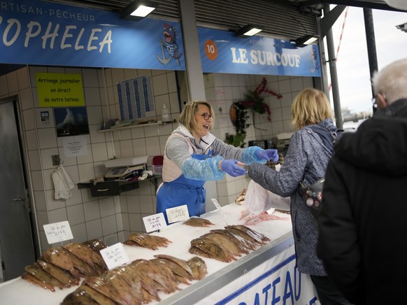 People buy fish at the market of the port of Boulogne-sur-Mer, northern France, Friday, Oct. 15, 2021. France wants more fishing licenses from London, but the UK is holding back. Britain's Brexit ...