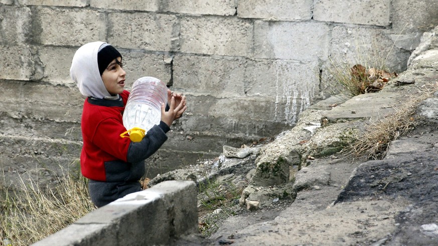 Ein syrischer Knabe trägt in Damaskus eine Flasche mit sauberem Wasser nach Hause.