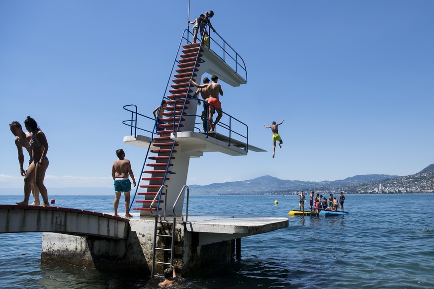 Kids jump from a diving platform into the Geneva Lake and enjoy sunny and warm weather, in Villeneuve, Southwestern Switzerland, Saturday, July 9, 2016. (KEYSTONE/Jean-Christophe Bott)