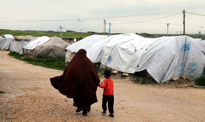 epa07473787 An unidentified woman, reportedly a wife of a suspected Islamic State (IS) fighter, walks with her son at Roj refugees camp in Hasakah, northeast of Syria, 30 March 2019. The camp which is ...