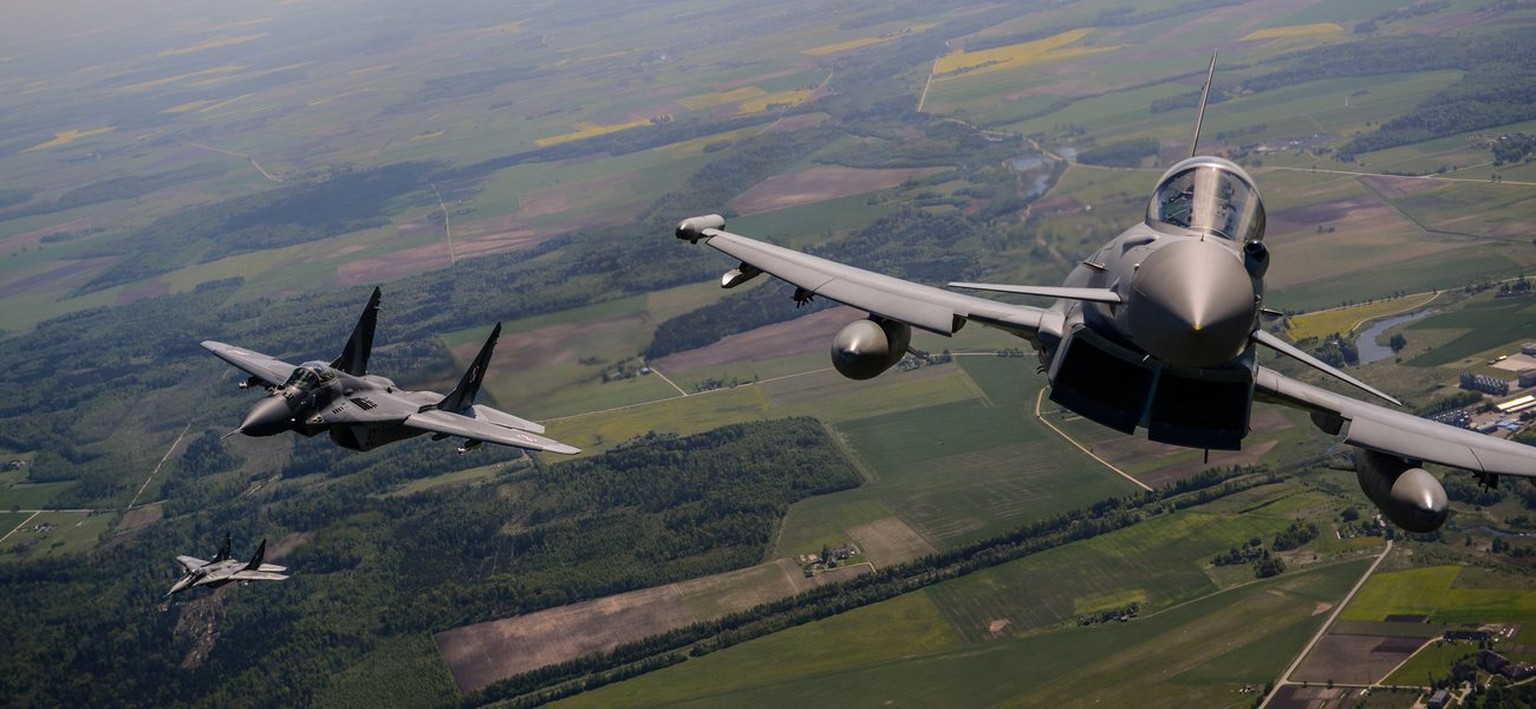 epa04208050 A British Royal Air Force Typhoon FGR4 aircraft (R) and two MIG-29 Fighters jet (L) of the Polish Air Force perform during a joint show in Siauliai Air Base, Lithuania, 15 May 2014. Polish ...