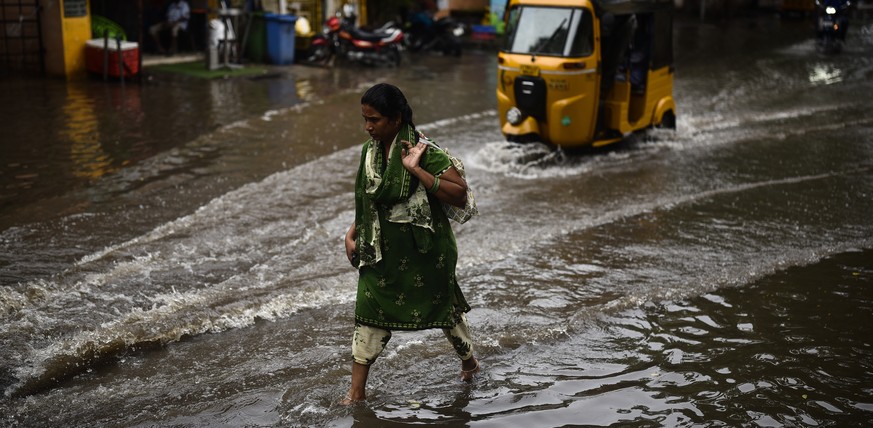 epa10300058 A resident passes through a waterlogged road following heavy rainfall, in Chennai, India, 11 November 2022. The Indian Meteorological Department (IMD) issued a red alert for four districts ...
