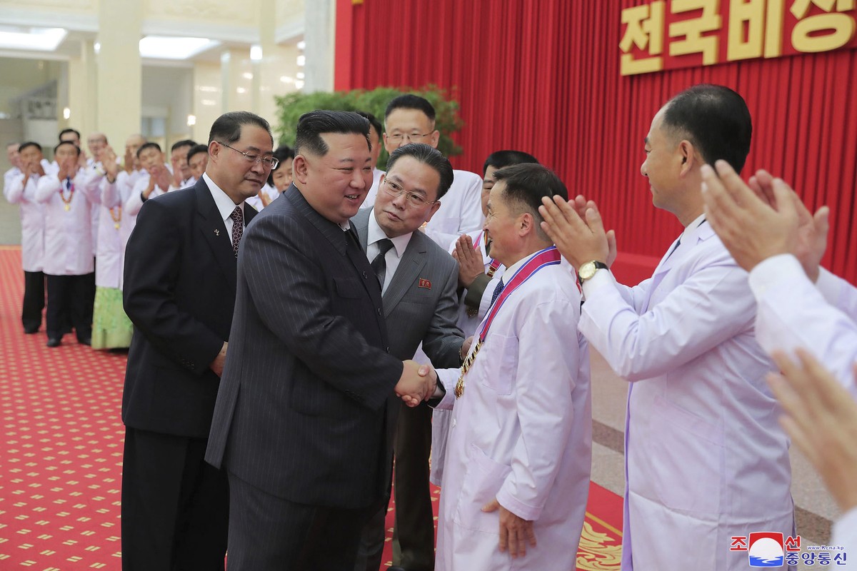 In this photo provided by the North Korean government, North Korean leader Kim Jong Un shakes hands with a health official in Pyongyang, North Korea, Wednesday, Aug. 10, 2022. Kim has declared victory ...