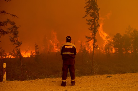 A firefighter stands at the scene of forest fire near Kyuyorelyakh village at Gorny Ulus area west of Yakutsk, in Russia, Saturday, Aug. 7, 2021. Wildfires in Russia's vast Siberia region endangered a ...