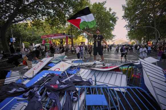 A protester waves a Palestinian flag on top of fences used as barricades to block the street to disrupt the twenty-first stage of the Spanish cycling race La Vuelta, from Alalpardo to Madrid, Spain, S ...