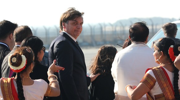 epa08158466 Brazilian President Jair Messias Bolsonaro (C) look back at Indian dancers performing upon his arrival at the New Delhi Airport, in New Delhi, India, 24 January 2020. President Bolsonaro i ...