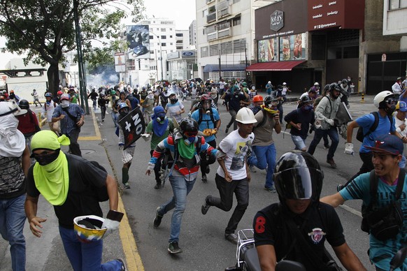 Anti-government demonstrators run away from security forces in Caracas, Venezuela, Wednesday, May 31, 2017. Protesters have flooded the streets of Venezuela for months, demanding new elections and fau ...