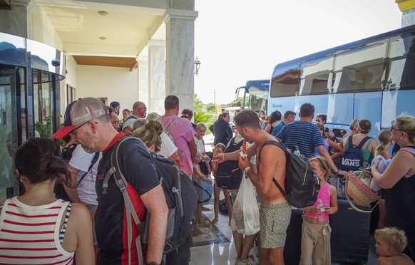 Evacuees wait to board buses as they leave their hotel during a forest fire on the island of Rhodes, Greece, Sunday, July 23, 2023. About 19,000 people have been evacuated from the Greek island of R...