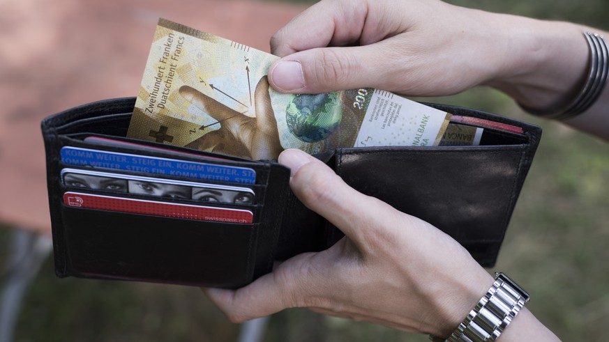 A person takes a 200 Swiss franc bill out of a wallet, pictured in Zurich, Switzerland, on August 23, 2018. (KEYSTONE/Christian Beutler)

Eine Person entnimmt eine 200-Franken-Banknote aus einem Porte ...