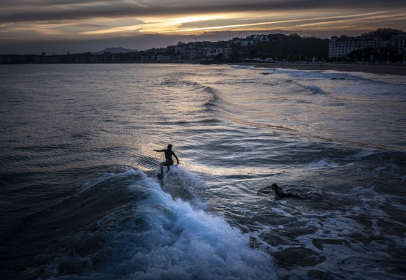 epaselect epa11113457 Two women surf at San Sebastian, Basque Country, Spain, 30 January 2024. Spain continues in a period of high pressure which has settled the weather conditions with high temperatu ...