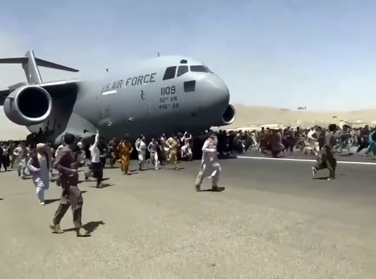 FILE - In this Apug. 16, 2021 file photo, hundreds of people run alongside a U.S. Air Force C-17 transport plane as it moves down a runway of the international airport, in Kabul, Afghanistan. Twin tra ...