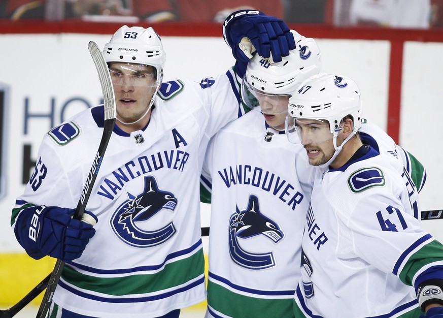 Vancouver Canucks&#039; Bo Horvat, left, celebrates his goal against the Calgary Flames with teammates Elias Pettersson, center, of Sweden, and Sven Baertschi, of Switzerland, during the first period  ...