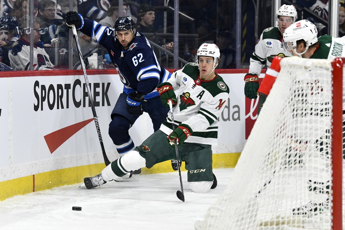 Minnesota Wild's Joel Eriksson Ek (14) passes the puck behind the net as he is checked by Winnipeg Jets' Nino Niederreiter (62) during the second period of an NHL hockey game Tuesday, Feb. 2 ...