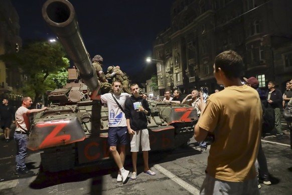 FILE - Soldiers of the Wagner Group military company sit atop a tank, while local civilians pose for a photo before leaving an area near the headquarters of the Confederate Military District on a street in R...
