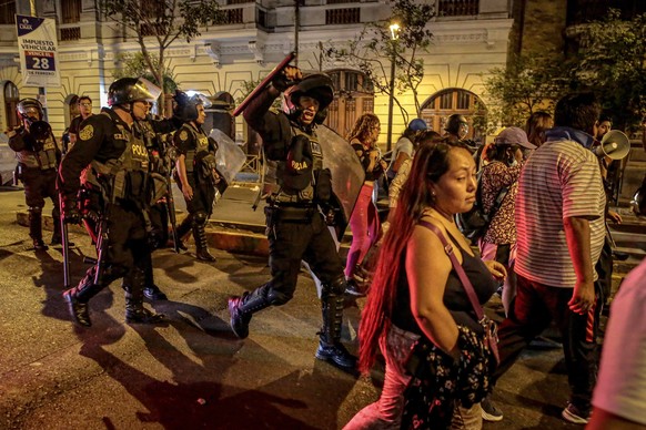 epa10458224 Police walk behind a group of people during an anti-government mobilization in the historic center of Lima, which brought together thousands of Peruvians who demanded the resignation of Pr ...