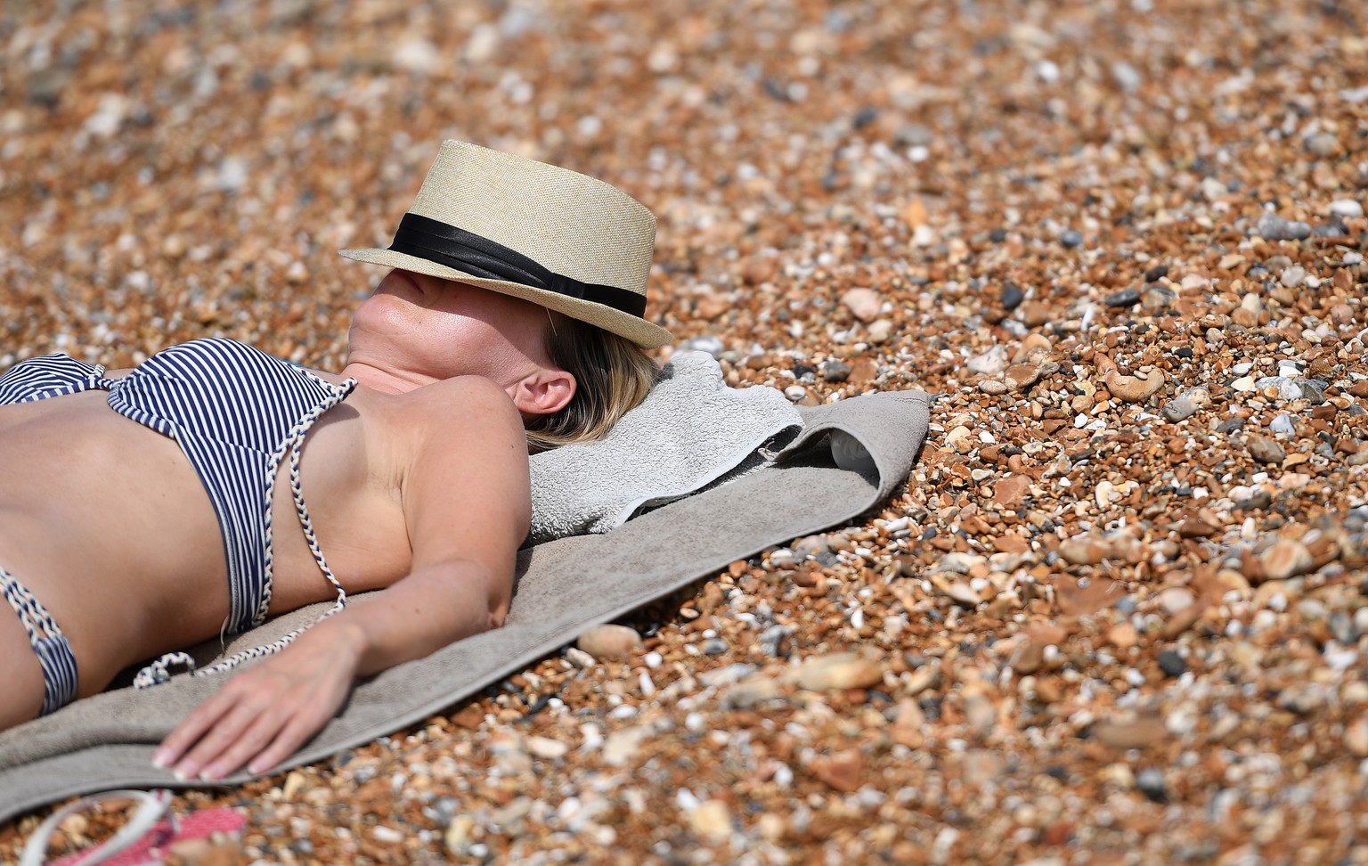 epa06911281 A woman covers her face against the sun on Brighton Beach in Britain July 26, 2018. Britain is about to experience its hottest day of the year with temperatures expected to reach close to 36 degrees ...