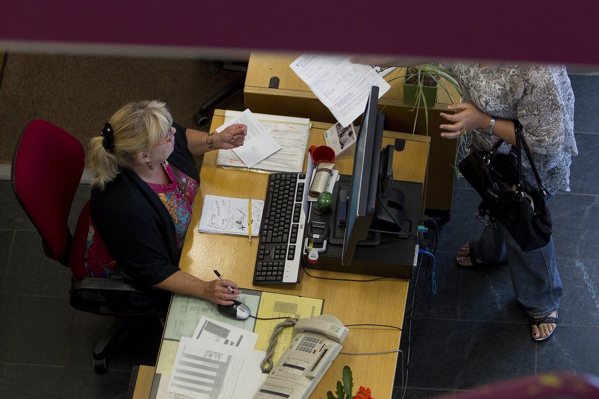 Une femme transmet un document a l'une des receptionistes de l'accueil du Centre d'action sociale des Paquis de l'Hospice general HG, ce mardi 14 septembre 2010 a Geneve. L’Hospice ...